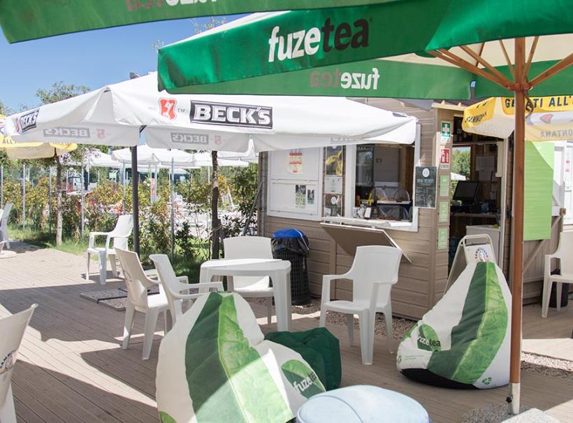 Chiosco all'aperto con sedie, tavoli e ombrelloni, marchiati Beck's e Fuze Tea.