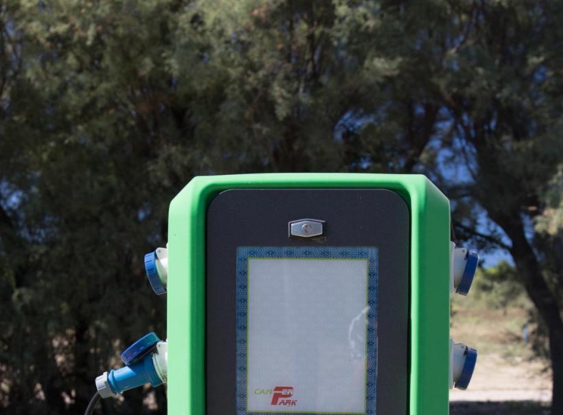 Colonnina verde per la ricarica elettrica con prese blu e schermo frontale.