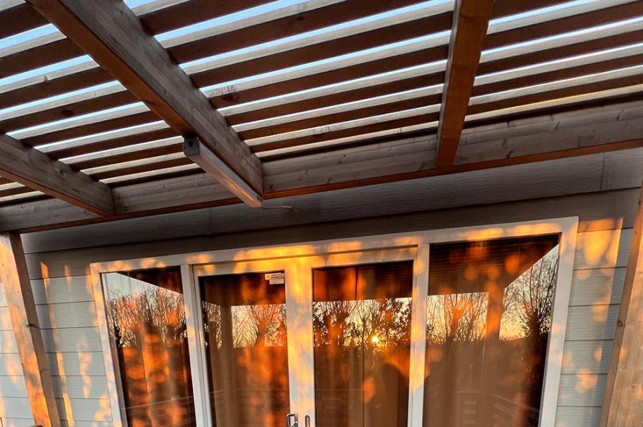 Terrazza in legno con porte finestre, illuminata dal tramonto.