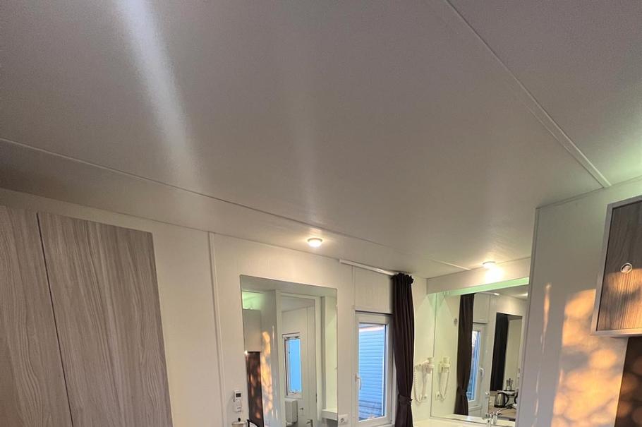 Camera moderna con armadio, mini frigo, scrivania e bagno annesso.