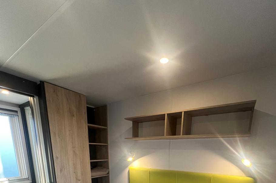 Camera da letto moderna con letto matrimoniale, testiera verde e copriletto blu.