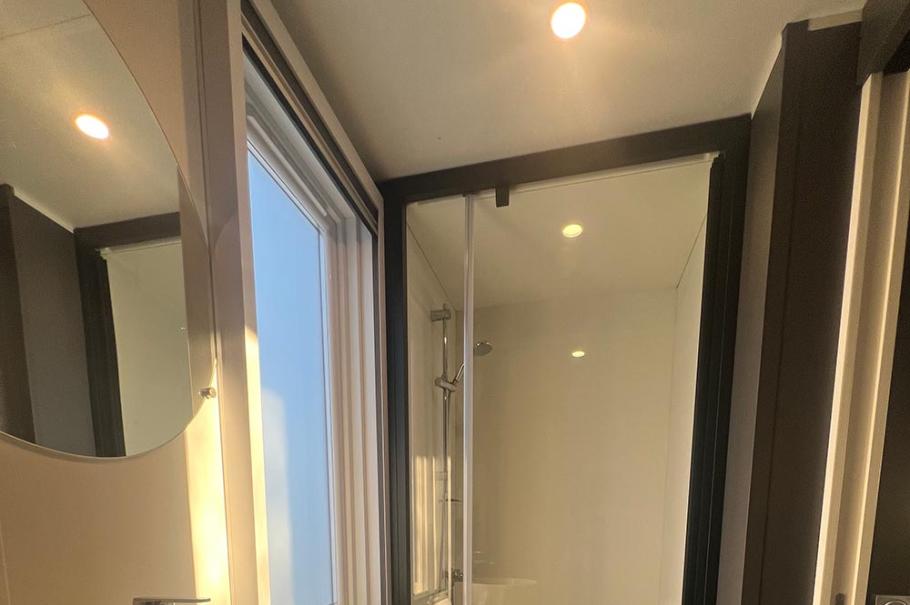 Bagno moderno con lavabo circolare, doccia in vetro e illuminazione soffusa.