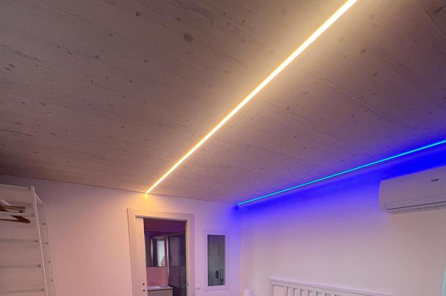 Camera da letto moderna con luci LED colorate e pavimento in legno.