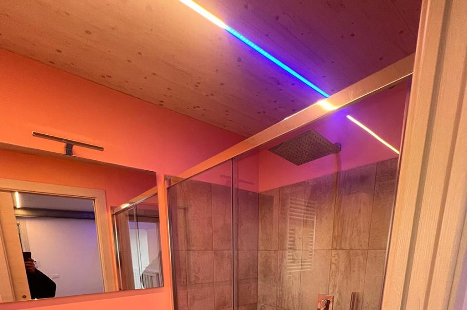 Bagno moderno con doccia in vetro, illuminazione a LED e lavabo sospeso.