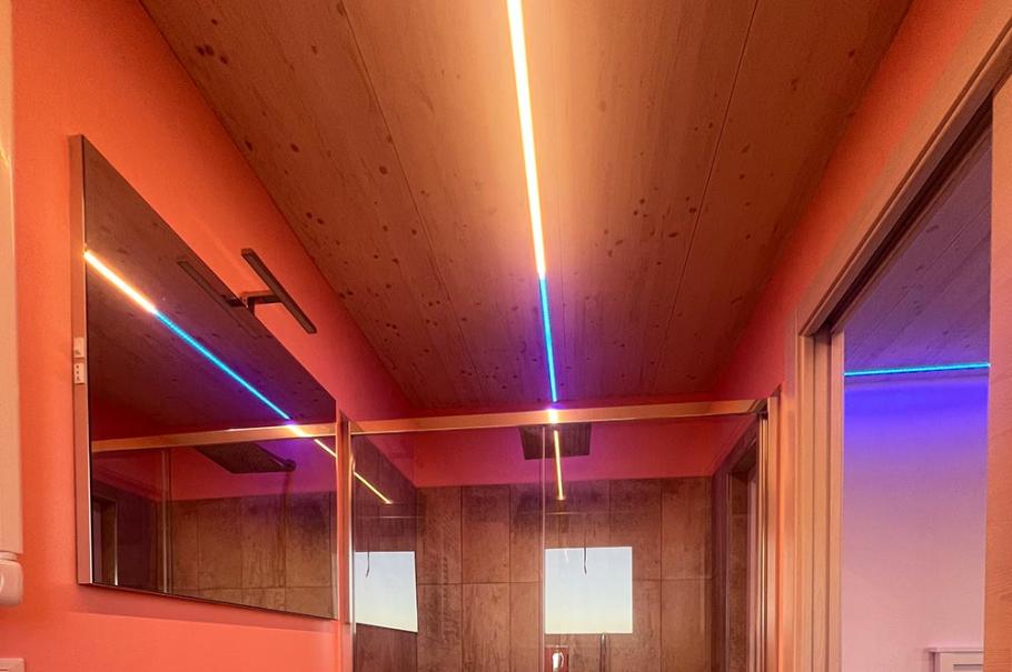 Bagno moderno con doccia a vetro, illuminazione LED e pareti color pesca.