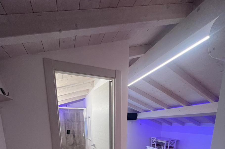 Camera moderna con soffitto in legno, illuminazione LED e pavimento in parquet.